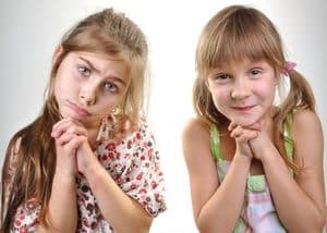 Portrait of two playful young girls asking for apologize or permission for something